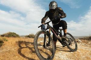 ciclista de descenso totalmente equipado con equipo de protección y su bicicleta foto