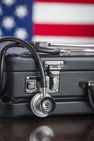 Briefcase and Stethoscope Resting on Table with American Flag Behind photo