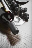 Abstract Wine Bottle, Glass and Grapes on Reflective Wood Surface photo