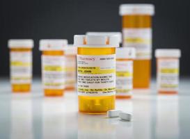 frascos de medicamentos y pastillas en una superficie reflectante con fondo gris foto