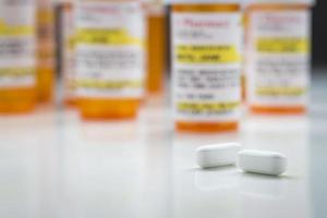 Medicine Bottles and Pills on Reflective Surface With Grey Background photo