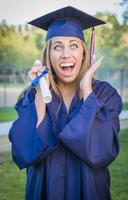 Expressive Young Woman Holding Diploma in Cap and Gown photo