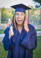 Expressive Young Woman Holding Diploma in Cap and Gown photo