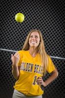 retrato de jugador de softbol femenino con pelota en el aire. foto