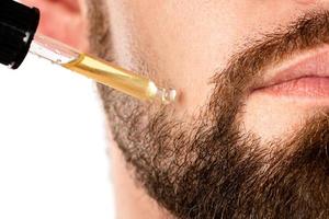 cara masculina y pipeta con aceite para el crecimiento de la barba foto