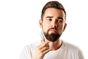 Handsome man trimming his beard with a scissors photo