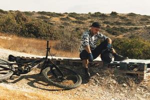 Bike rider relaxing after downhill race on bicycle in a mountains photo