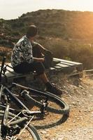 Bike rider relaxing after downhill race on bicycle in a mountains photo