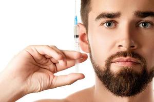 Handsome man holding syringe with a filler on white background photo