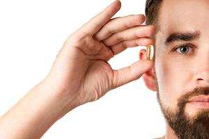 Man holding capsule with a fish or krill oil source of fatty acids such as DHA and EPA photo