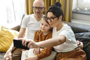 Happy family taking selfie using smartphone at home photo