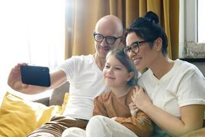 familia feliz tomando selfie usando un teléfono inteligente en casa foto