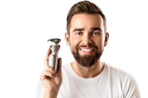 Handsome bearded man holding electric shaver in his hand photo