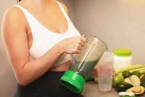 Pregnant woman make a green protein cocktail at home photo