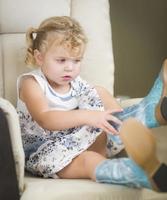 Blonde Haired Blue Eyed Little Girl Putting on Cowboy Boots photo