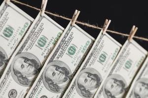 Hundred Dollar Bills Hanging From Clothesline on Dark Background photo