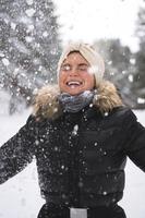 Young cheerful girl enjoying snowfall during beautiful winter day photo