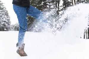 Woman wearing sheepskin boots is kicking snow photo