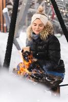 Beautiful woman warming up by the fire pit during cold winter day photo