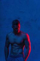 Bodybuilder is posing in the colorful neon light photo
