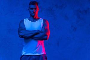 Handsome and confident bodybuilder posing in colorful light photo