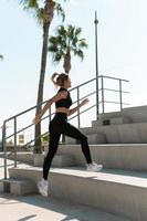 Athletic woman is running on concrete stairs during her summer workout photo