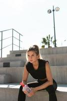 Tired woman with a bottle of water after her summer workout photo