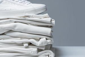 Stack of white clothes and stylish trainers photo