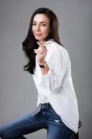 Beautiful middle aged fashion model wearing white shirt and jeans in a photo studio