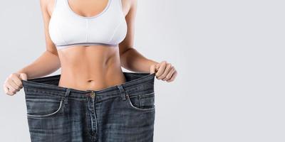 Woman showing result after weight loss wearing on old jeans photo