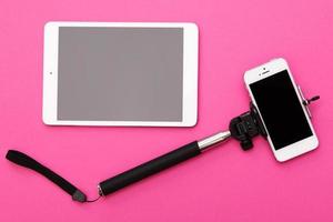 teléfono inteligente en un selfie stick y tablet pc foto
