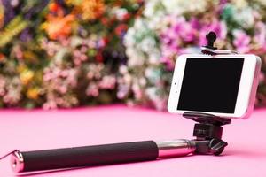 Selfie stick on background with flowers photo