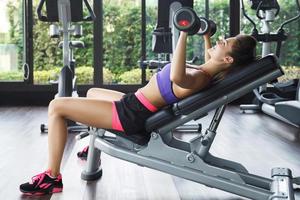 Woman working out with dumbbells in gym. Incline bench press. photo