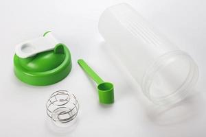 Green protein shaker and scoop on white photo