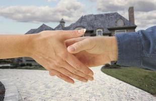 Man and woman shaking hands in front of a new house. photo