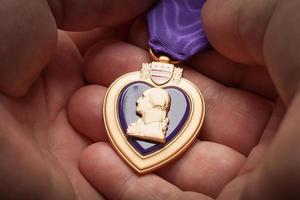 Male Hand Holding the Armed Forces Purple Heart Metal photo