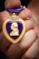 mano masculina sosteniendo las fuerzas armadas corazón púrpura metal foto