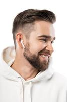 Handsome bearded man in white clothes using wireless earbuds on white background photo