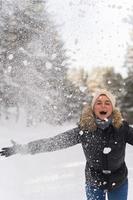 Woman throwing snow into the air during cold winter day. Selective focus. photo