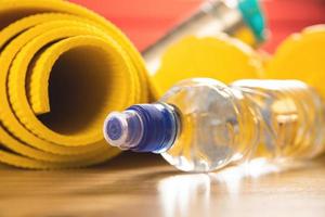 Bottle of still water and yellow fitness mat photo