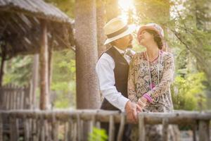 Pareja romántica vestida de los años 20 en un puente de madera foto