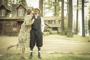 Pareja romántica vestida de 1920 frente a una vieja cabaña foto