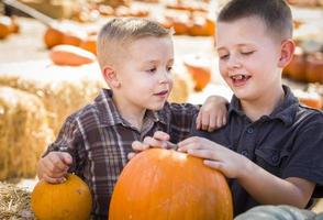 dos niños divirtiéndose en el huerto de calabazas en un día de otoño. foto