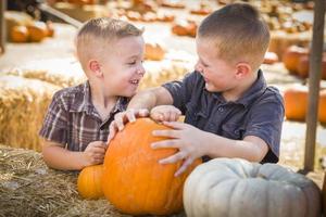 dos niños divirtiéndose en el huerto de calabazas en un día de otoño. foto