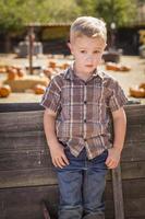 Adorable Little Boy Standing Against Old Wood Wagon at Pumpkin Patch in Rural Setting. photo