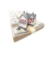 Small House on Row of Hundred Dollar Bill Stacks Isolated on a White Background photo