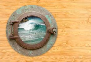 Antique Porthole with View of Crashing Waves on a Bamboo Wall Background. photo