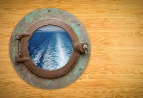 ojo de buey antiguo en la pared de bambú con vista al sendero del océano del barco foto