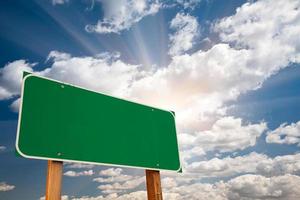 Blank Green Road Sign Over Clouds and Sunburst photo