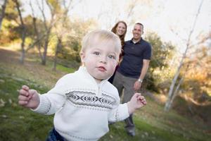 Cute Young Boy Walking as Parents Look On From Behind photo